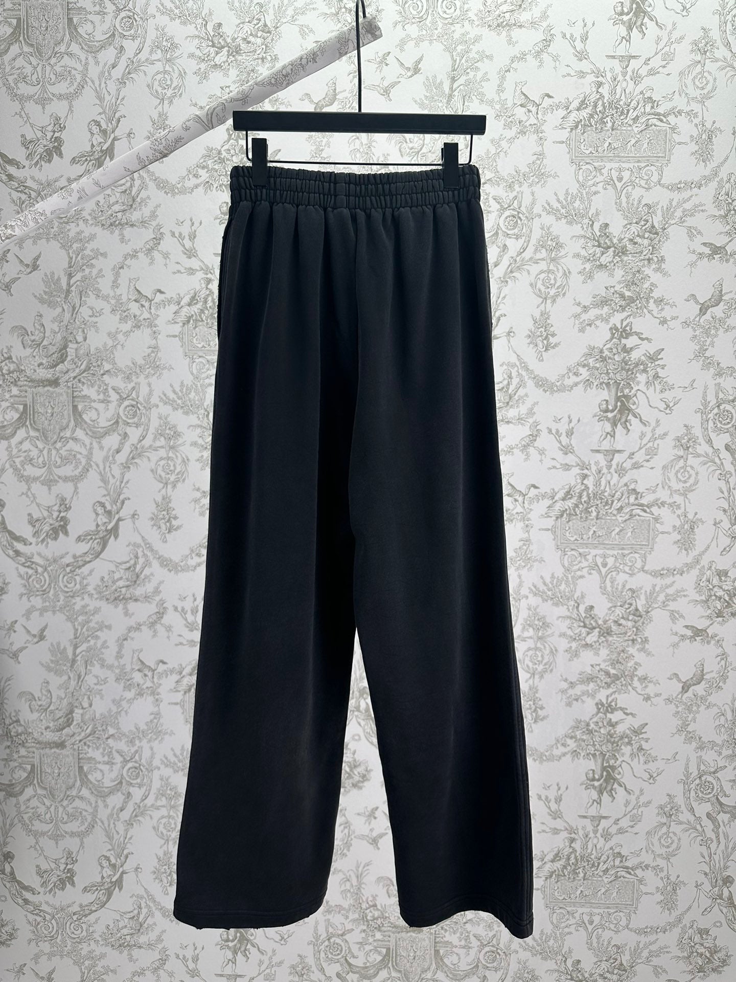 Balenciaga dark wide-leg pants, front view, elastic waistband and logo patch
