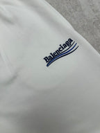 White pants with embroidered Balenciaga logo patch and blue stripe detail.