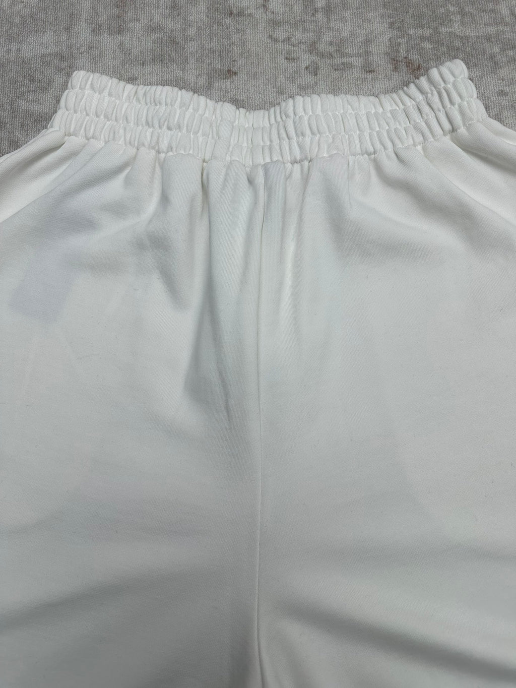 White wide-leg pants with elastic waistband and vertical seam lines, front view.