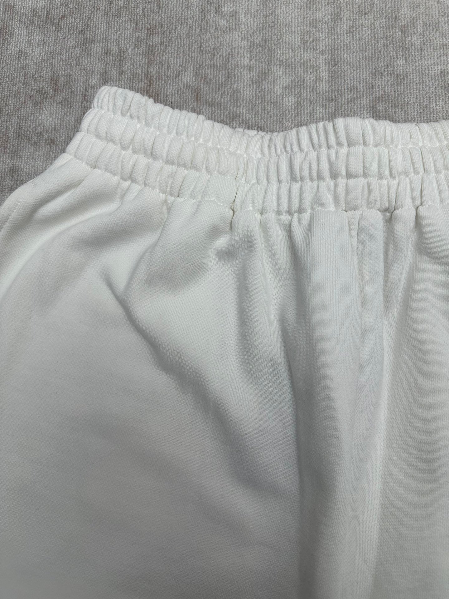 White pants waistband with gathered elastic and smooth fabric, close-up.