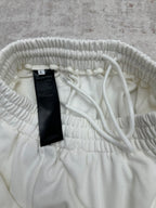 White pants waistband with interior drawstring and size tag, close-up.