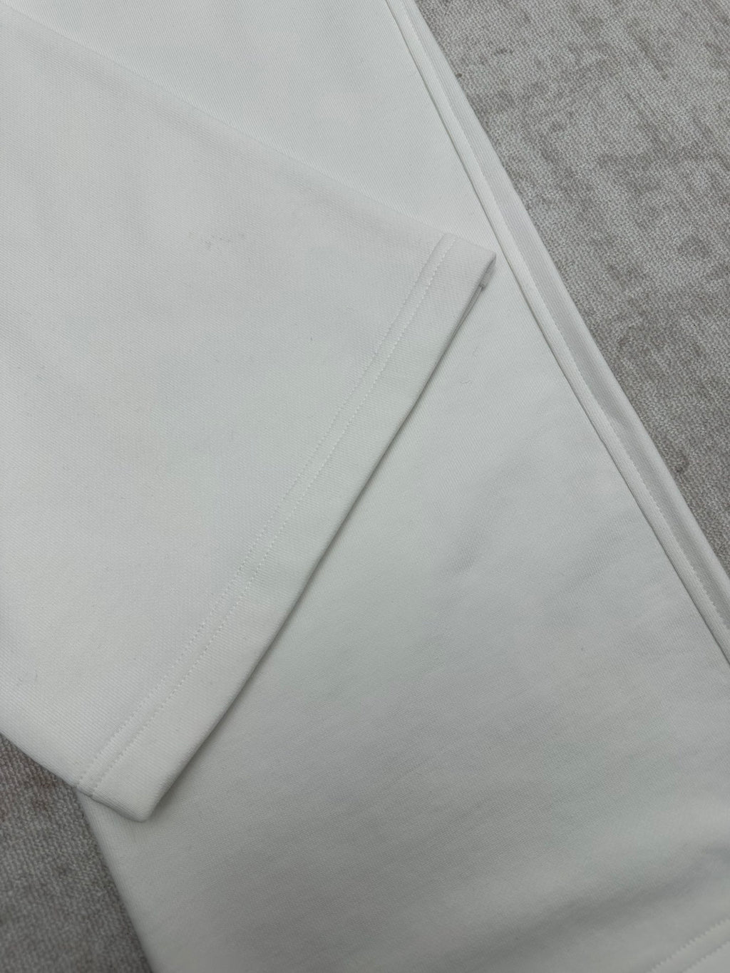 White pants hem detail with smooth seams, close-up on the lower leg.