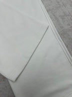 White pants hem detail with smooth seams, close-up on the lower leg.