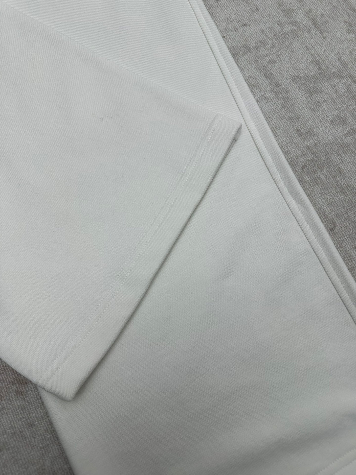 White pants hem detail with smooth seams, close-up on the lower leg.