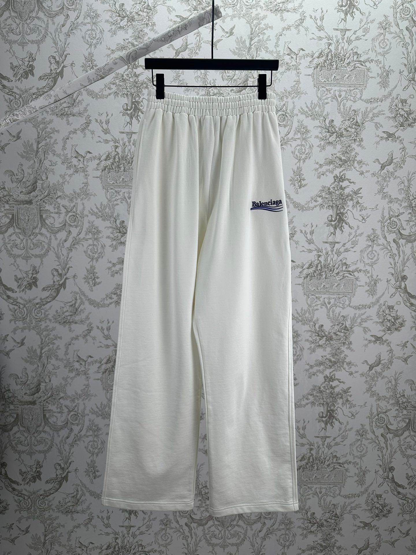 White wide-leg pants with elastic waistband and small Balenciaga logo on the leg.