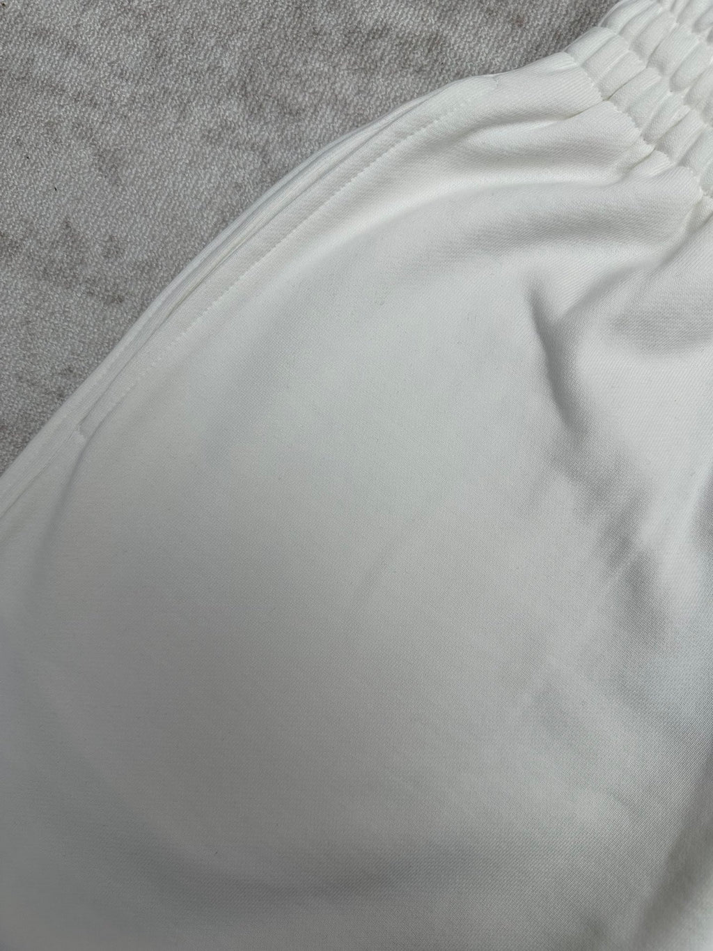 White pants fabric with gathered waistband detail, close-up view.