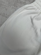 White pants fabric with gathered waistband detail, close-up view.