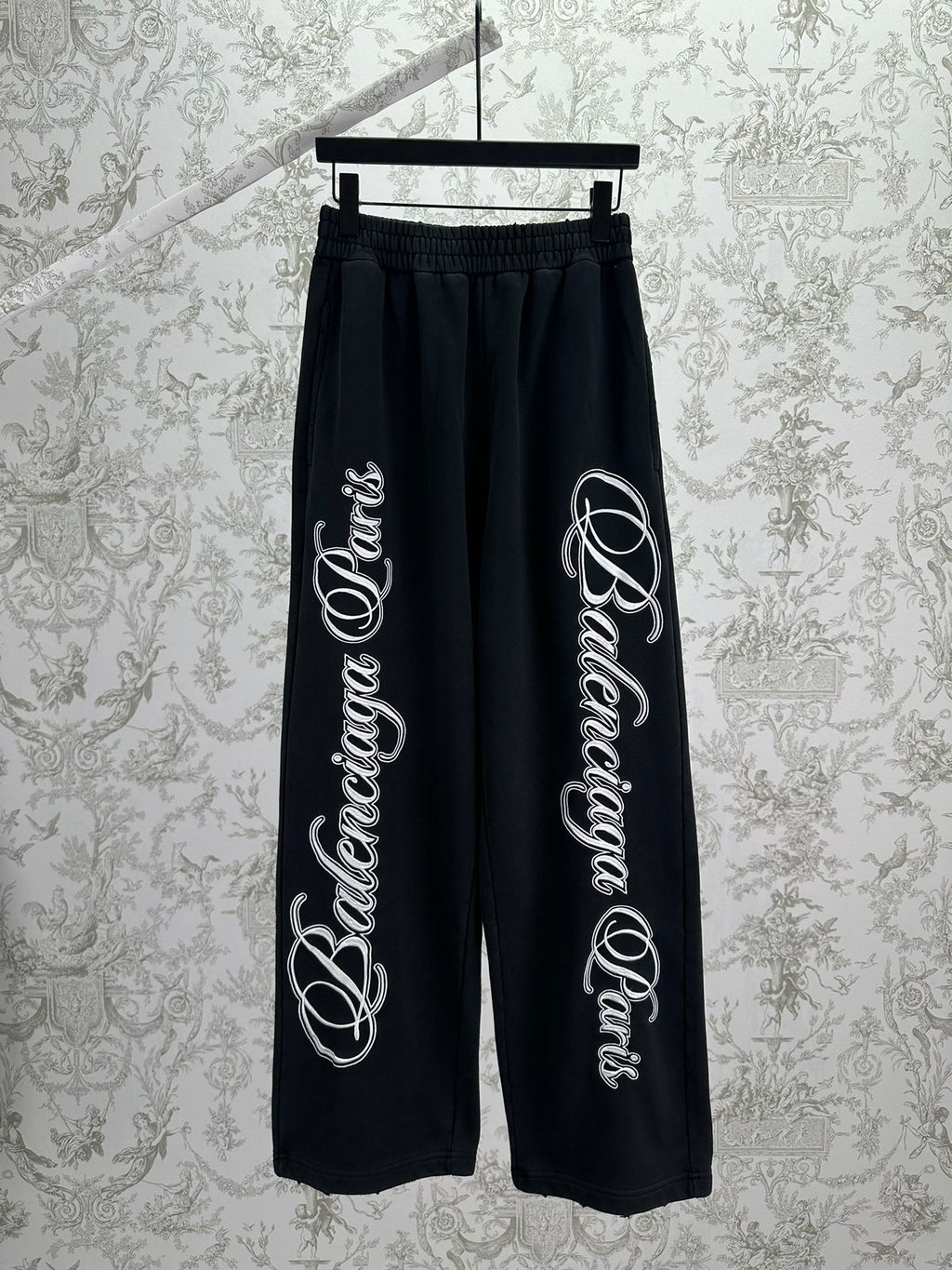 Black Balenciaga track pants with elastic waistband and large white script logo