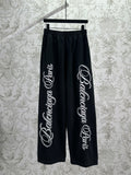 Black Balenciaga track pants with elastic waistband and large white script logo