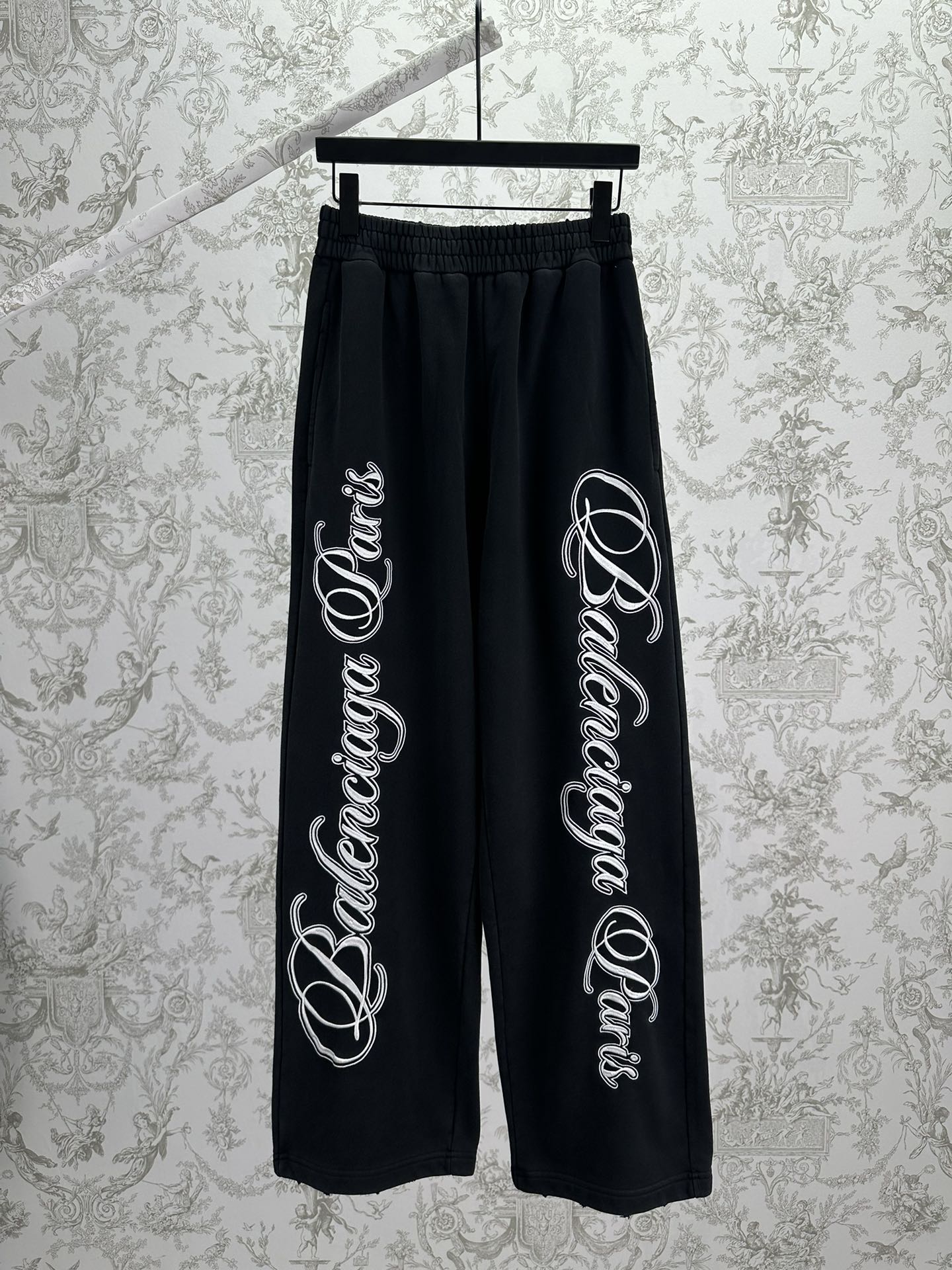 Black Balenciaga track pants with elastic waistband and large white script logo