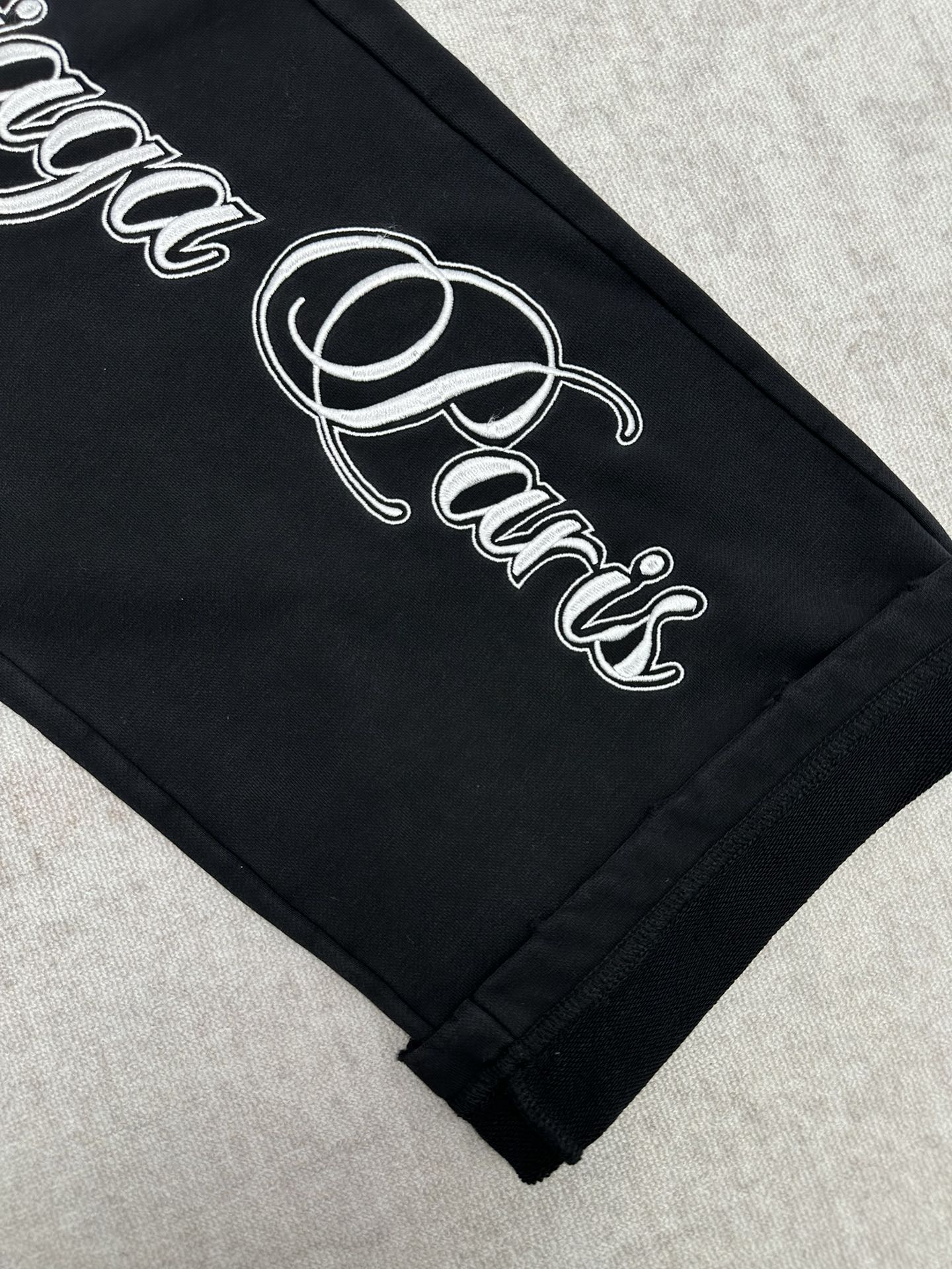 Black pants hem with white cursive logo print