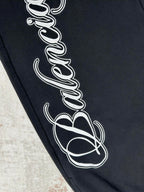 Black pants fabric close-up with white outlined script print on leg