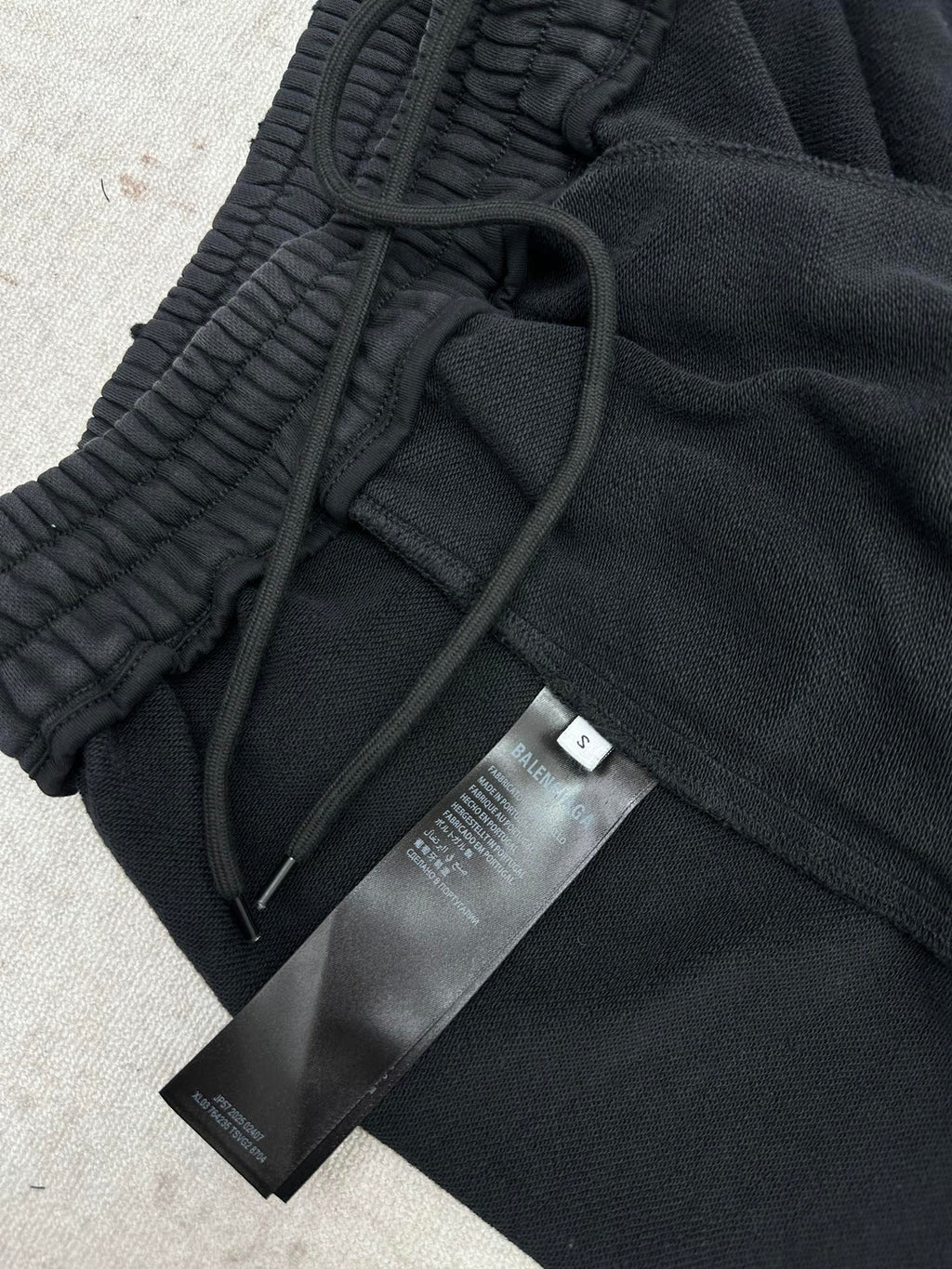 Black track pants with drawstring and fabric tags attached