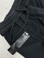 Black track pants with drawstring and fabric tags attached