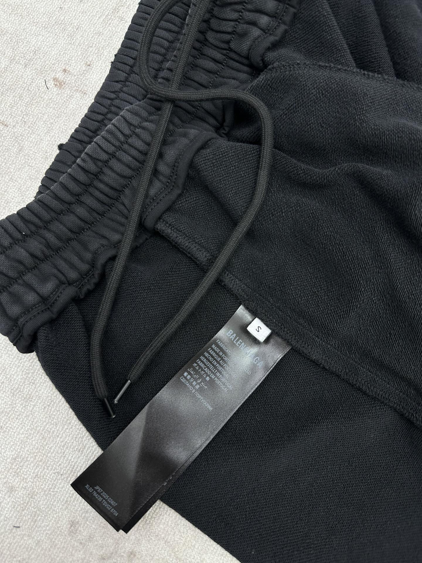Black track pants with drawstring and fabric tags attached