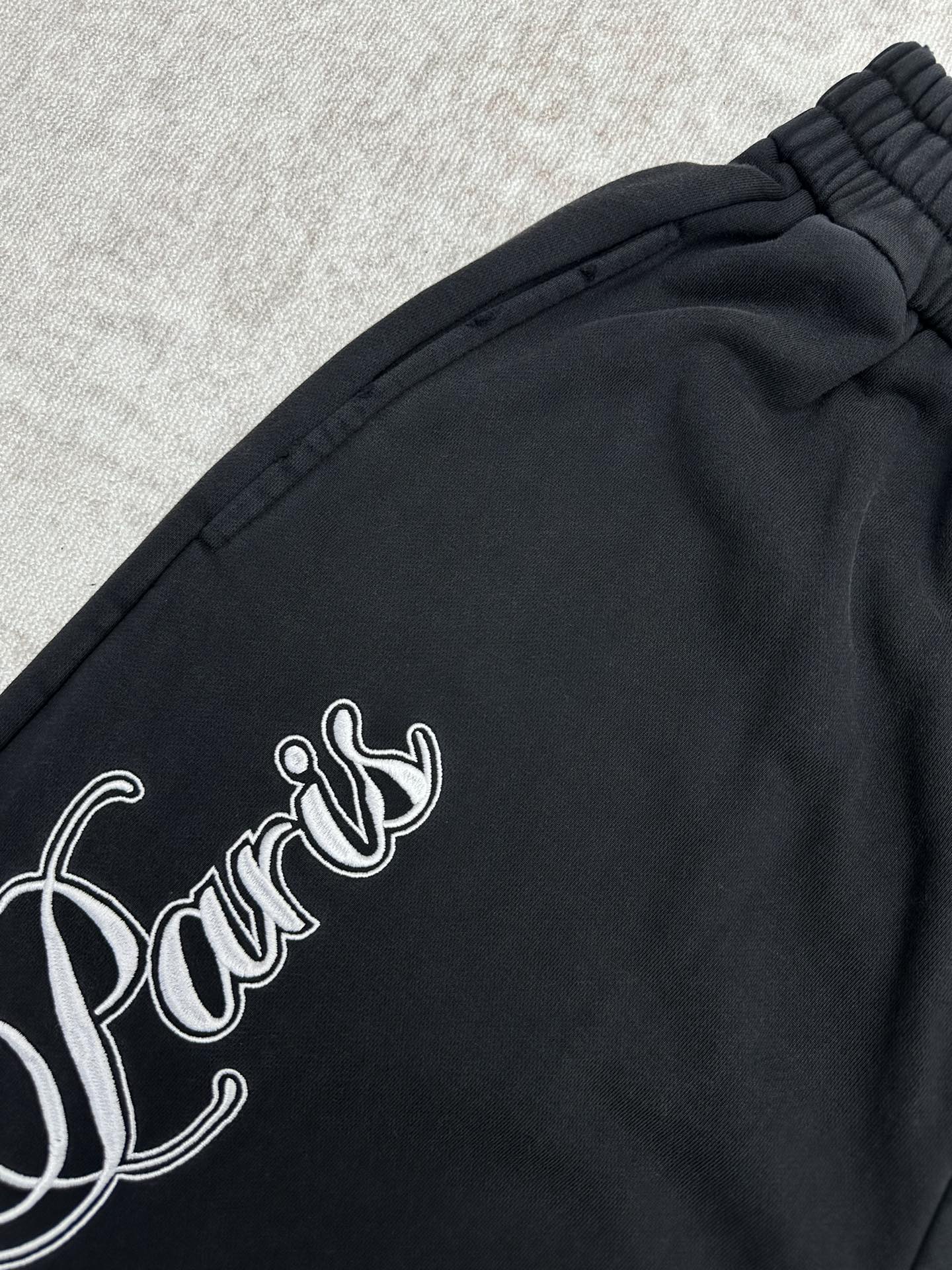 Black pants with white cursive logo across the side panel