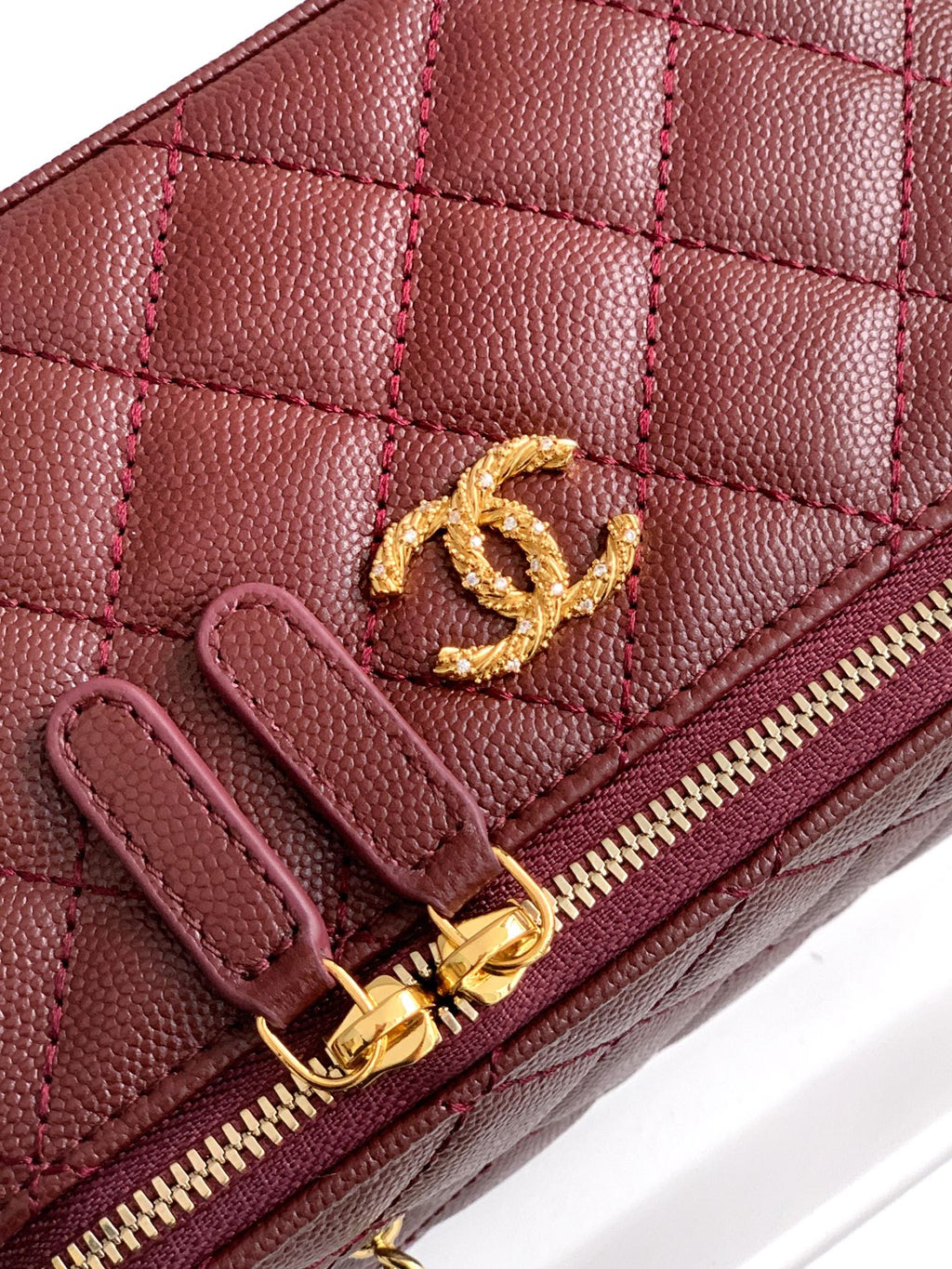 Close-up of burgundy Chanel quilted mini bag with gold CC logo and zipper