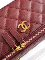 Close-up of burgundy Chanel quilted mini bag with gold CC logo and zipper