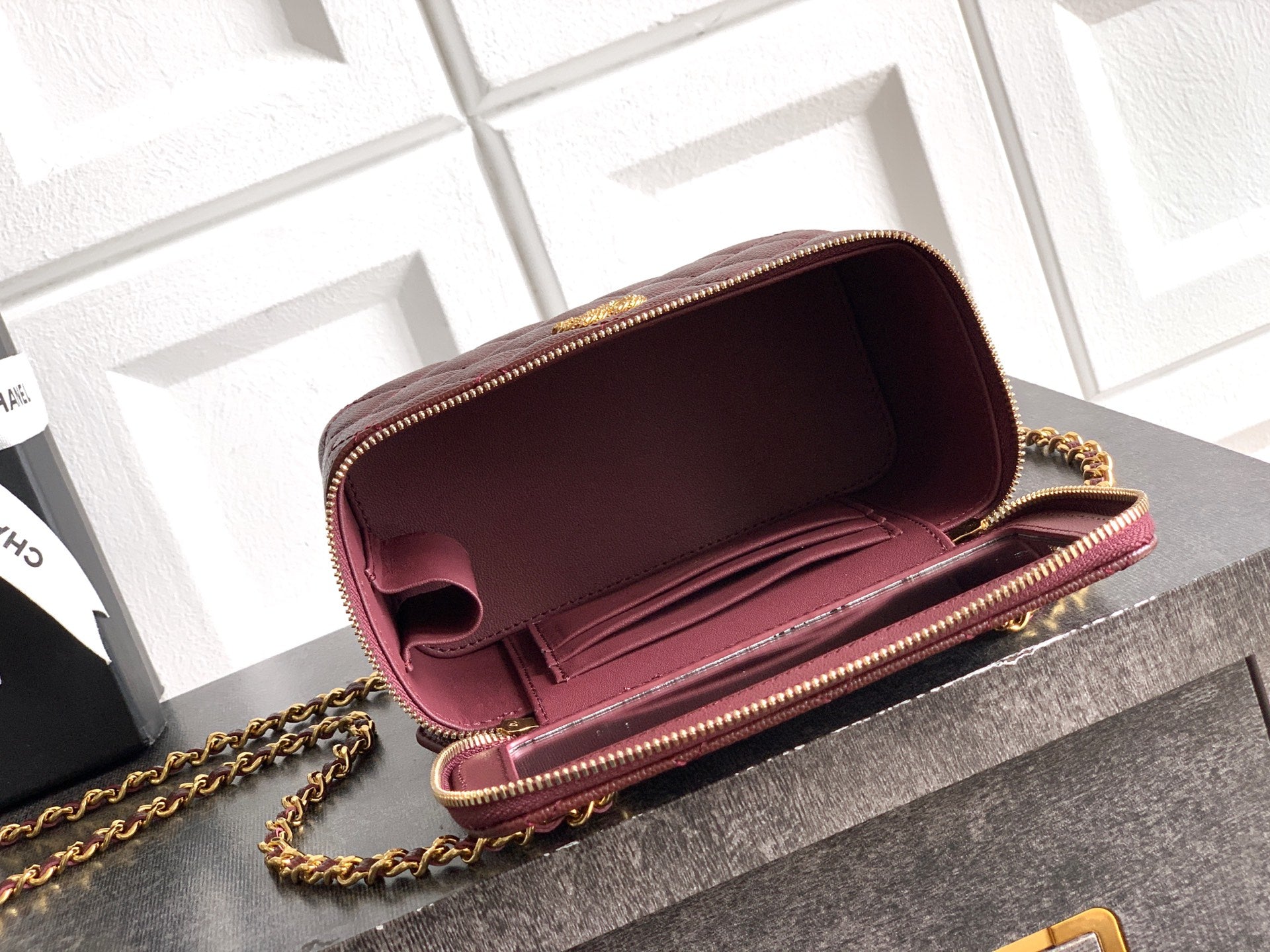 Burgundy Chanel mini flap bag open with interior showing and gold chain strap