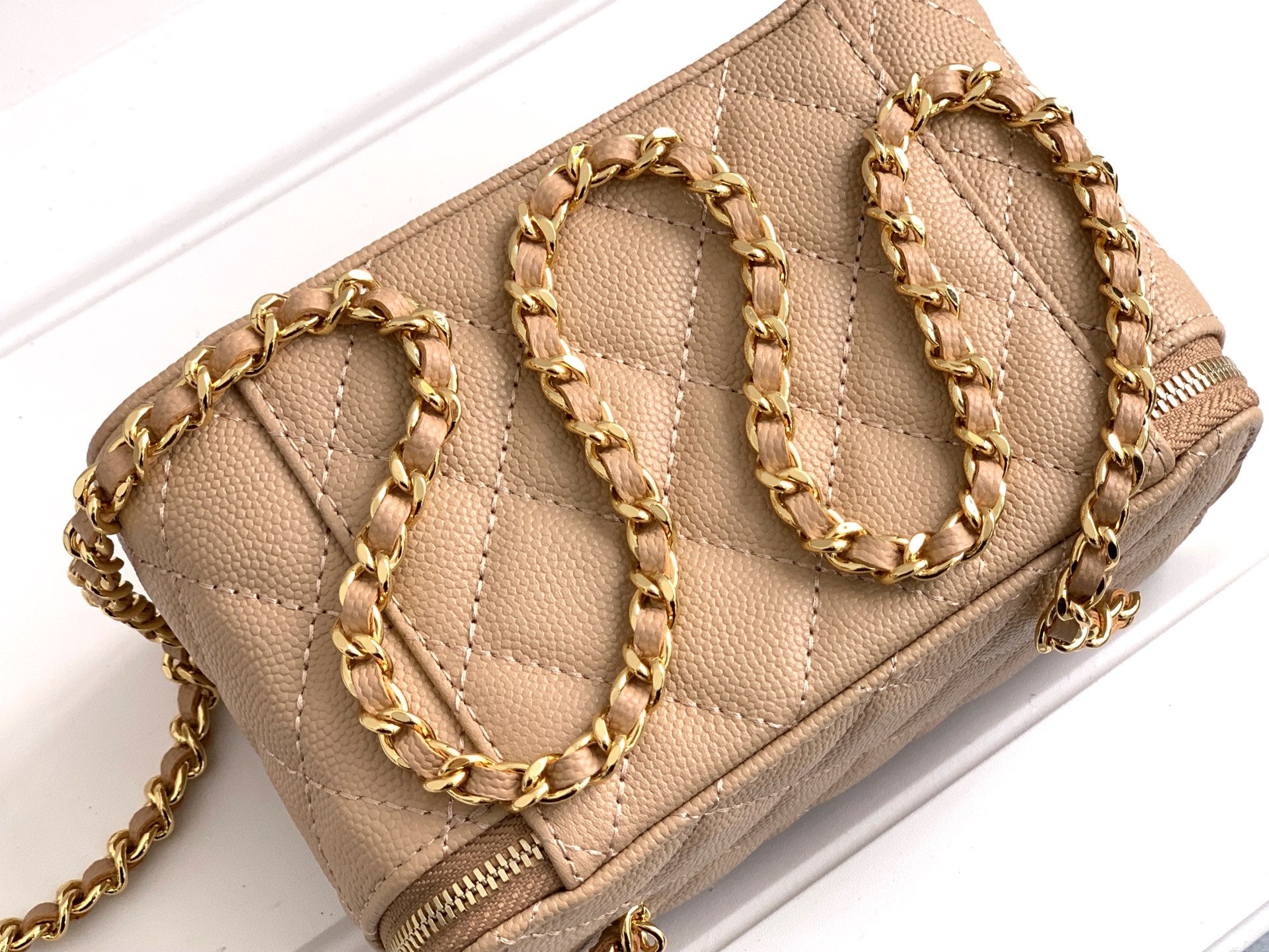 Chanel quilted mini bag top view, beige, gold chain strap and zipper edge