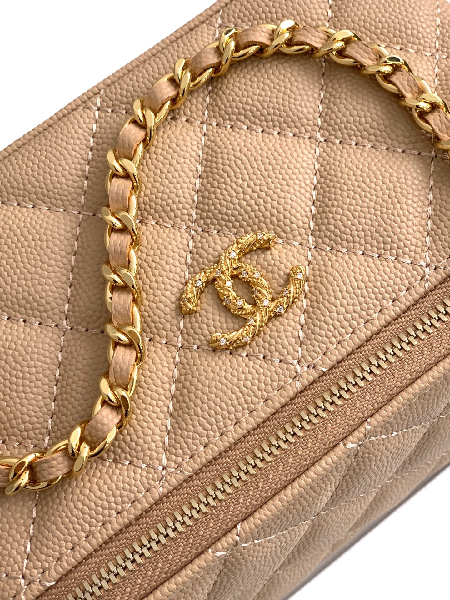 Chanel quilted mini bag close-up, beige leather, gold CC emblem and chain