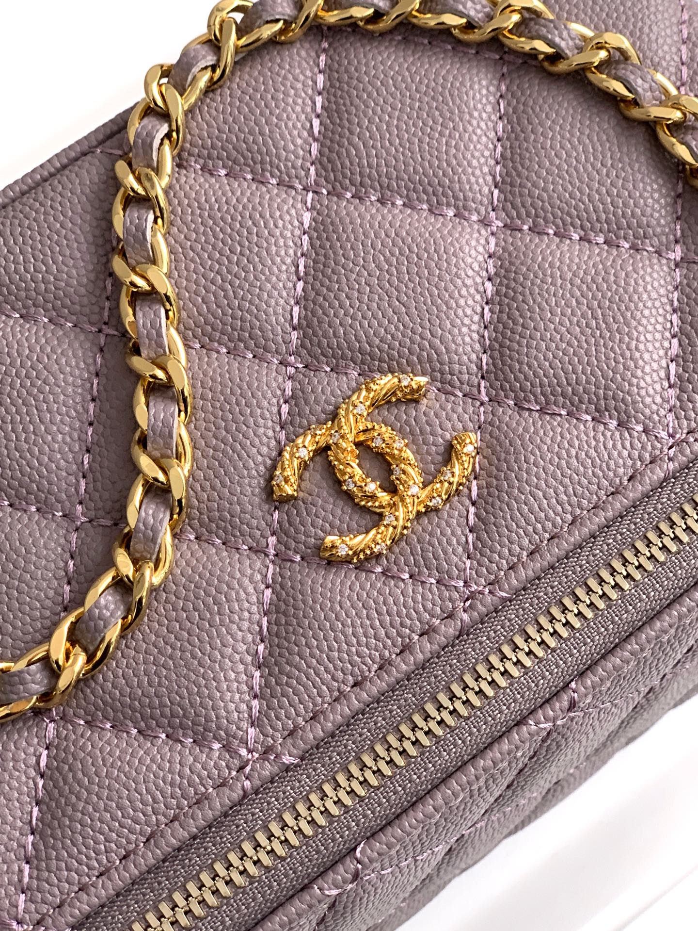 Close-up of lilac quilted bag front with gold-tone Chanel CC logo