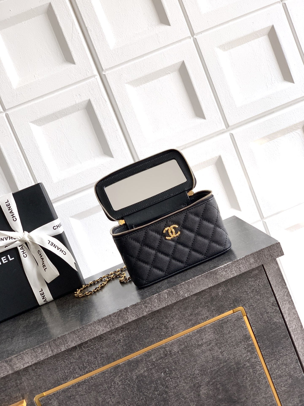 Chanel mini bag with quilted black leather, open flap, gold-tone chain strap.