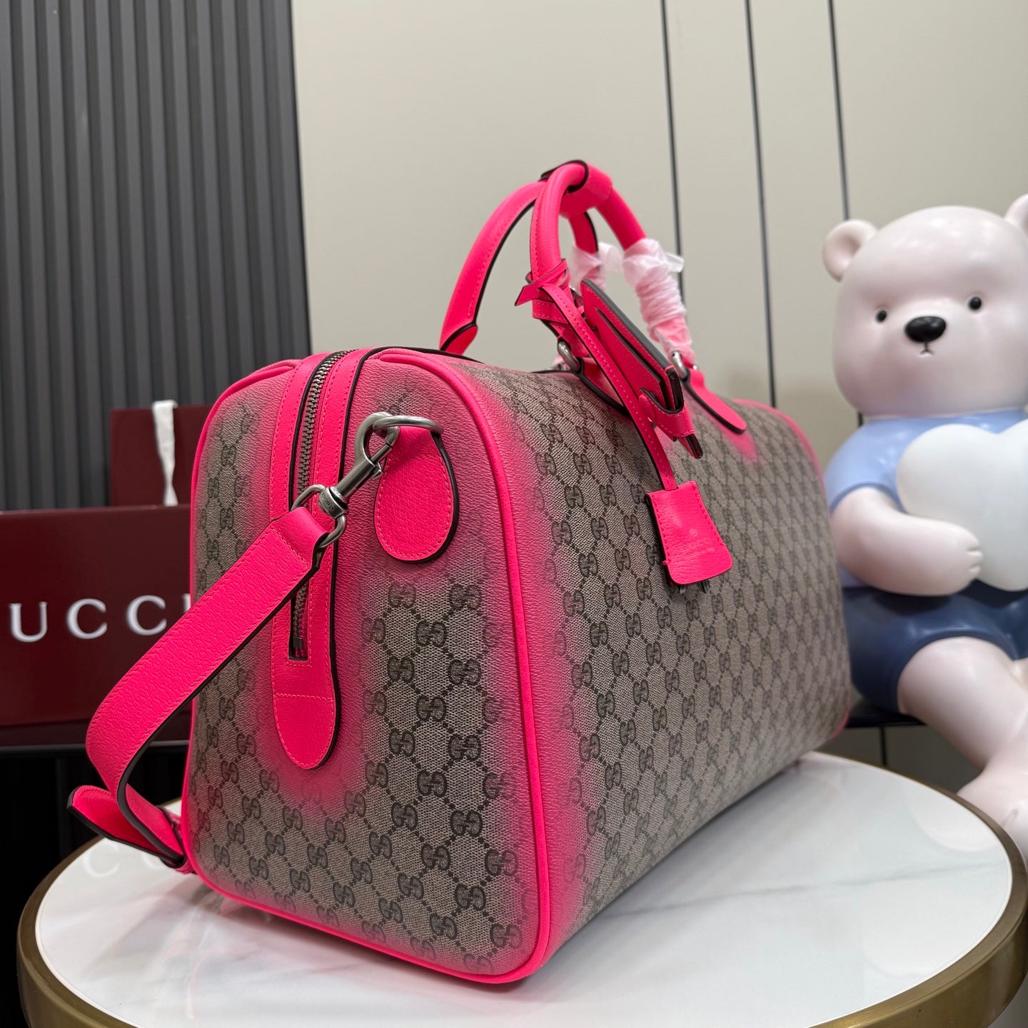 Gucci duffel bag side view with pink strap, GG canvas, and metal hardware