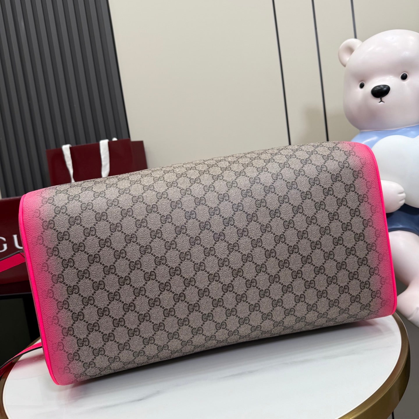 Gucci duffel bag close-up of GG canvas body with bright pink trim and handle