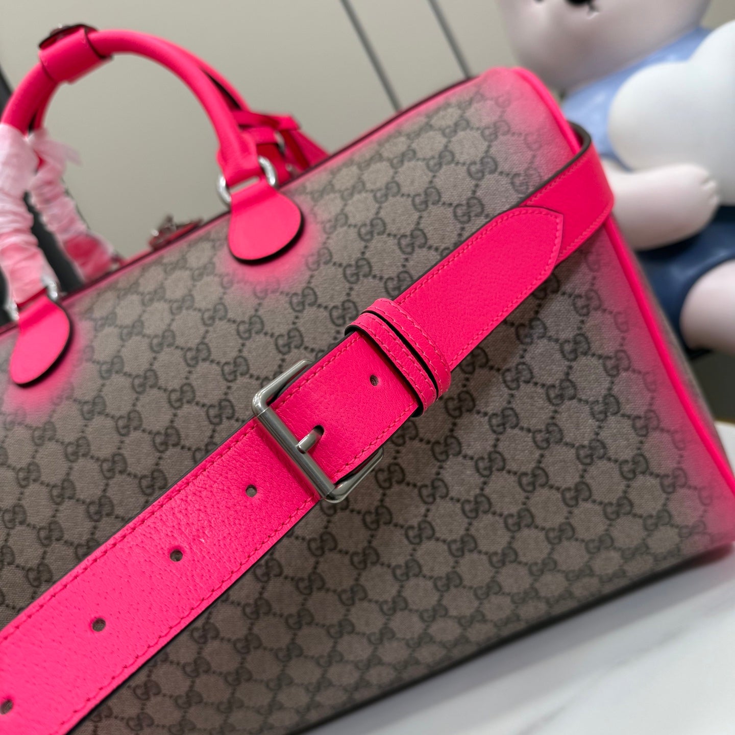 Gucci duffel bag crossbody strap with silver buckle and bright pink leather tab