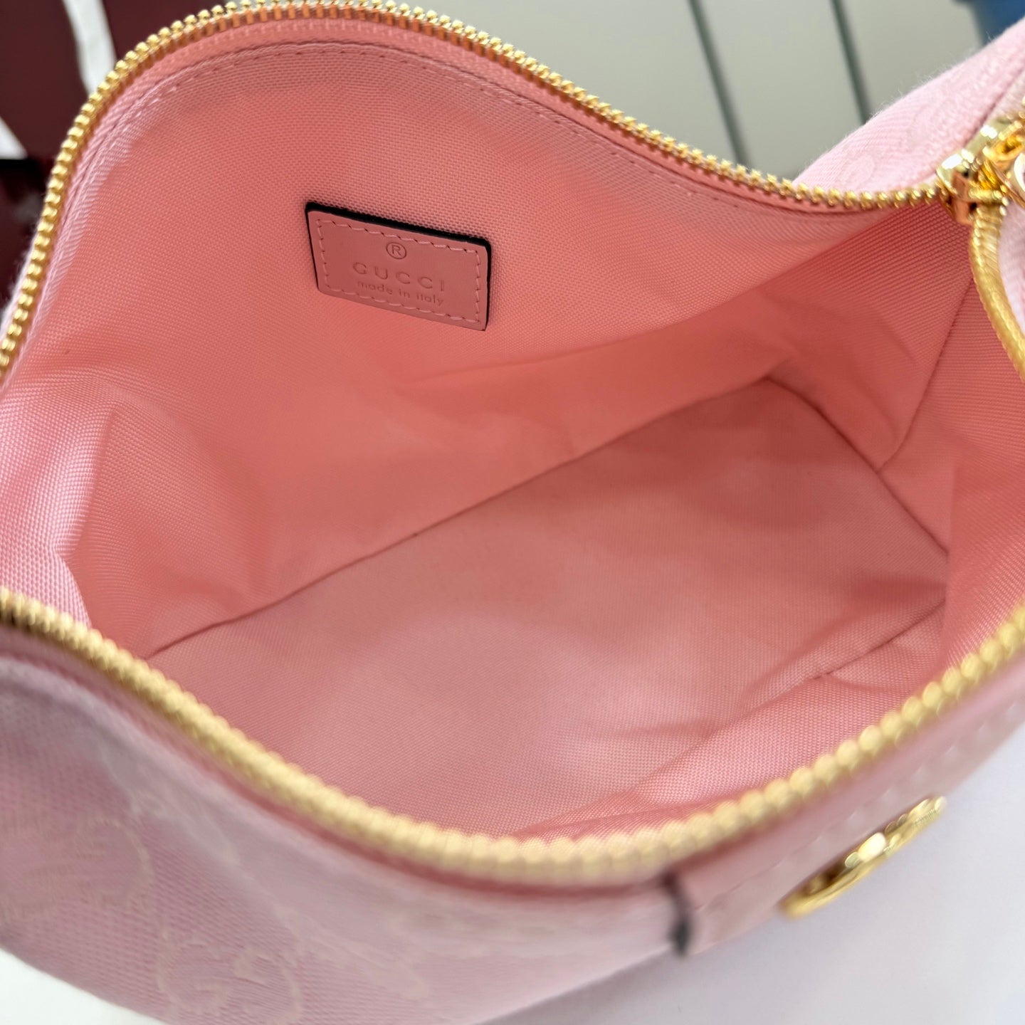 Pink fabric-lined bag interior with gold zipper trim