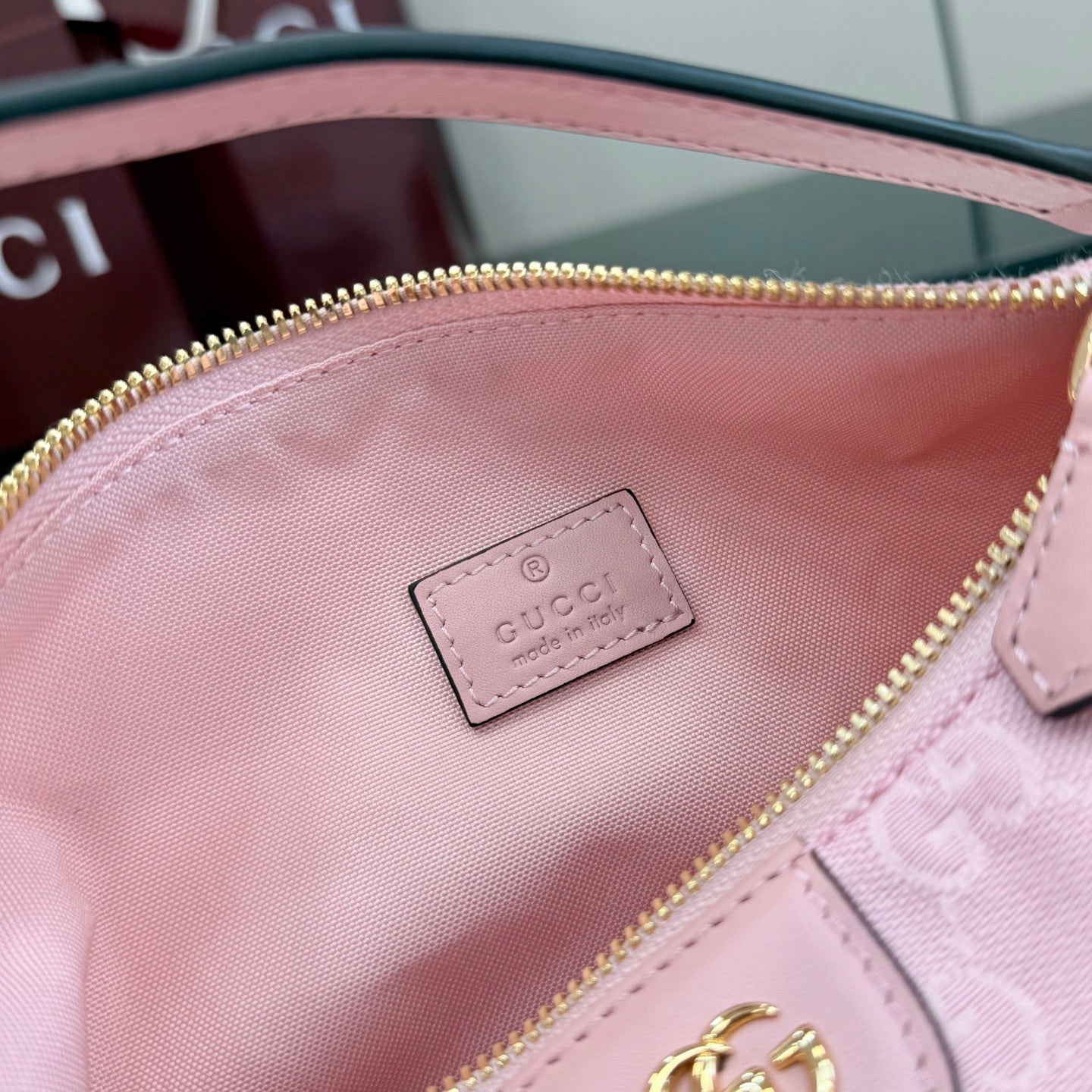 Pink inner pocket with designer logo patch and gold zipper edge