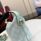 Small handbag with light teal leather handle tab, gold-tone clasp, monogram fabric.