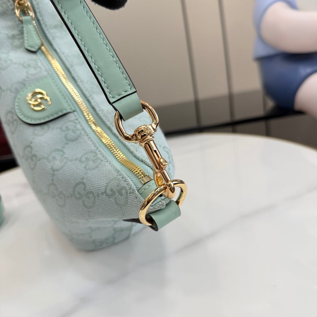 Gucci bag close-up of gold D-ring strap hardware and light blue leather trim