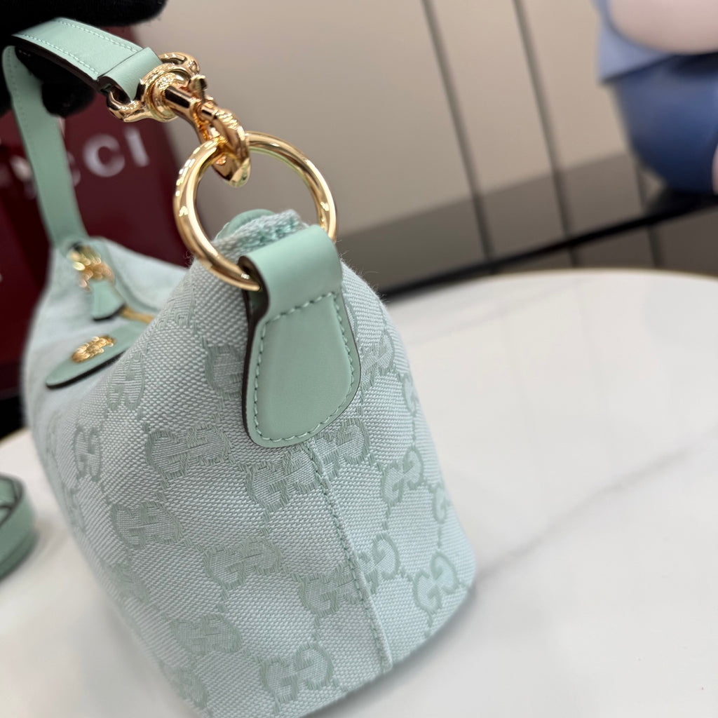 Small handbag with light teal leather strap and gold-tone ring, monogram fabric.