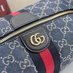 Gucci GG canvas bag close-up: navy fabric, gray leather tab, red stripe, gold zipper pull.