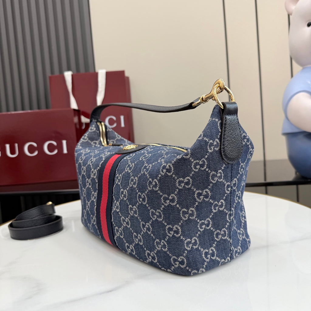 Gucci GG canvas shoulder bag with navy monogram print and red stripe, top handle visible.