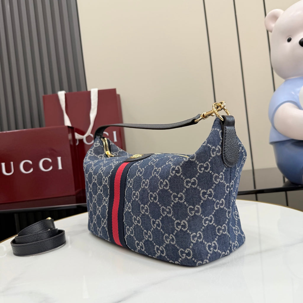 Gucci GG canvas shoulder bag, navy with red stripe, curved top handle and gold hardware.