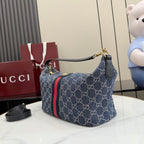 Gucci GG canvas shoulder bag, navy with red stripe, curved top handle and gold hardware.