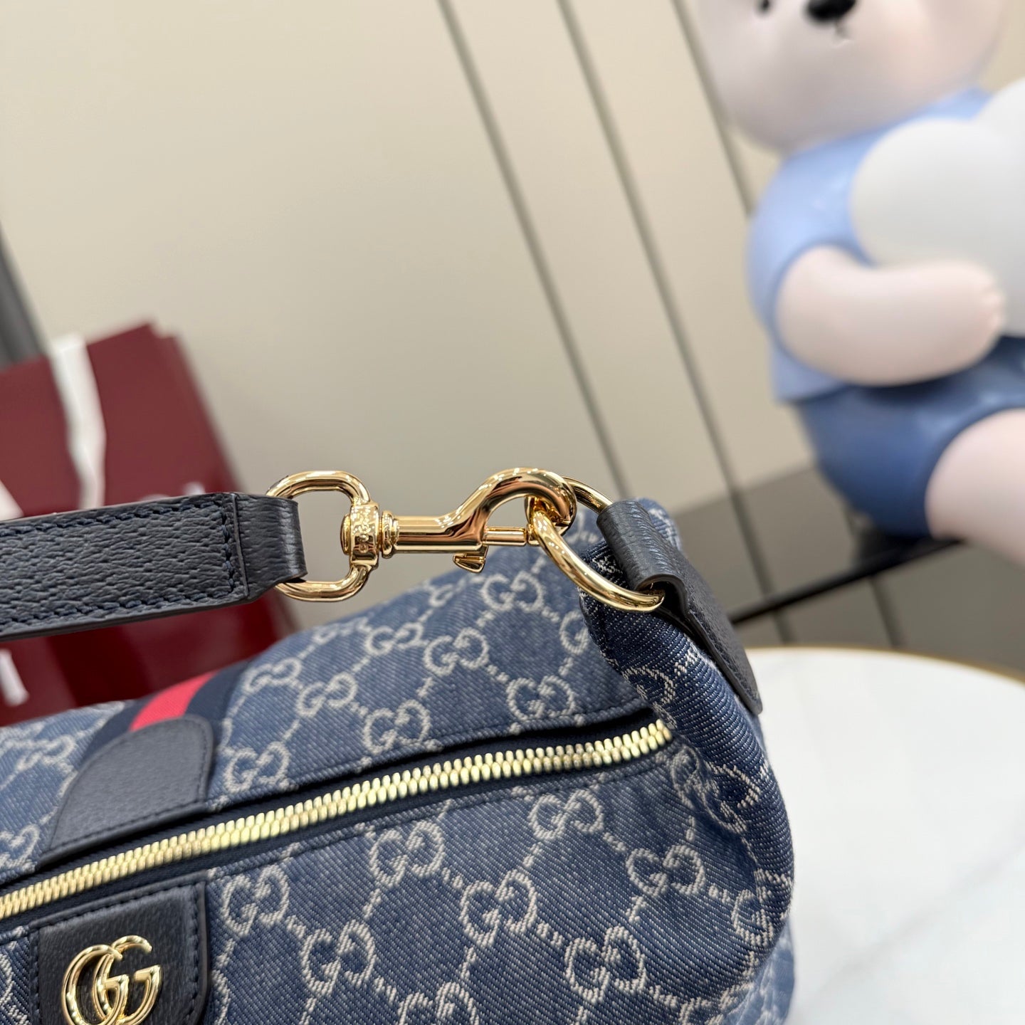 Gucci GG canvas shoulder bag close-up of strap hardware with gold rings and leather ends.