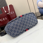 Gucci GG canvas shoulder bag laid on its side, navy monogram with red stripe trim.