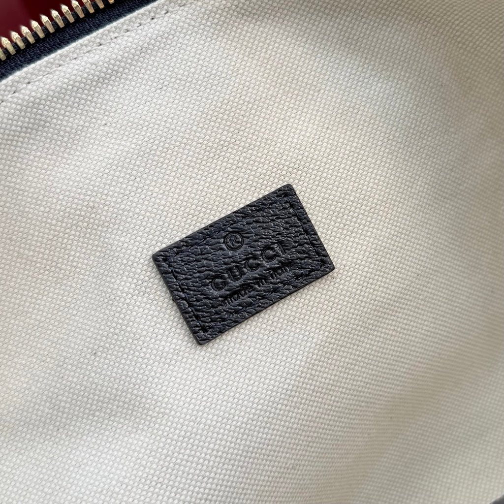 Gucci GG canvas bag lining close-up showing black leather brand patch.