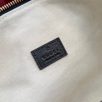Gucci GG canvas bag lining close-up showing black leather brand patch.