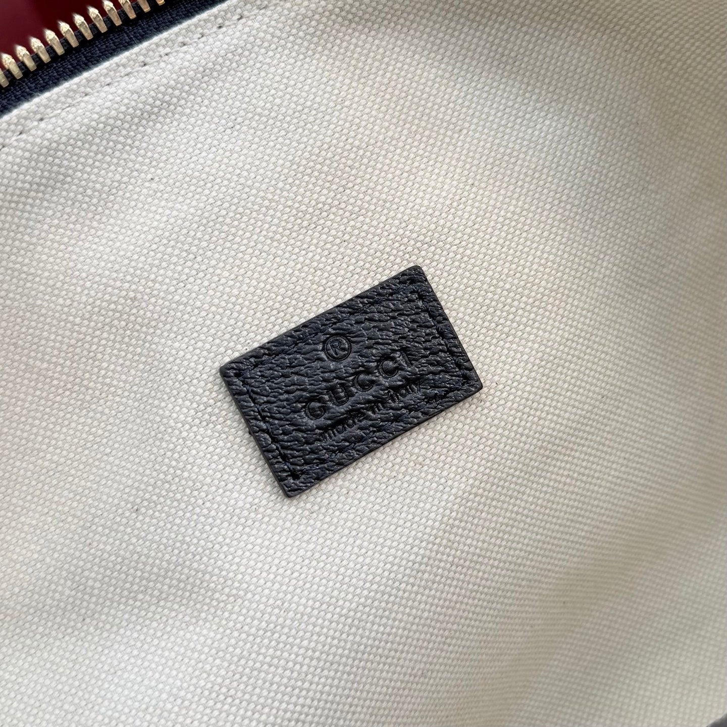 Gucci GG canvas bag lining close-up showing black leather brand patch.