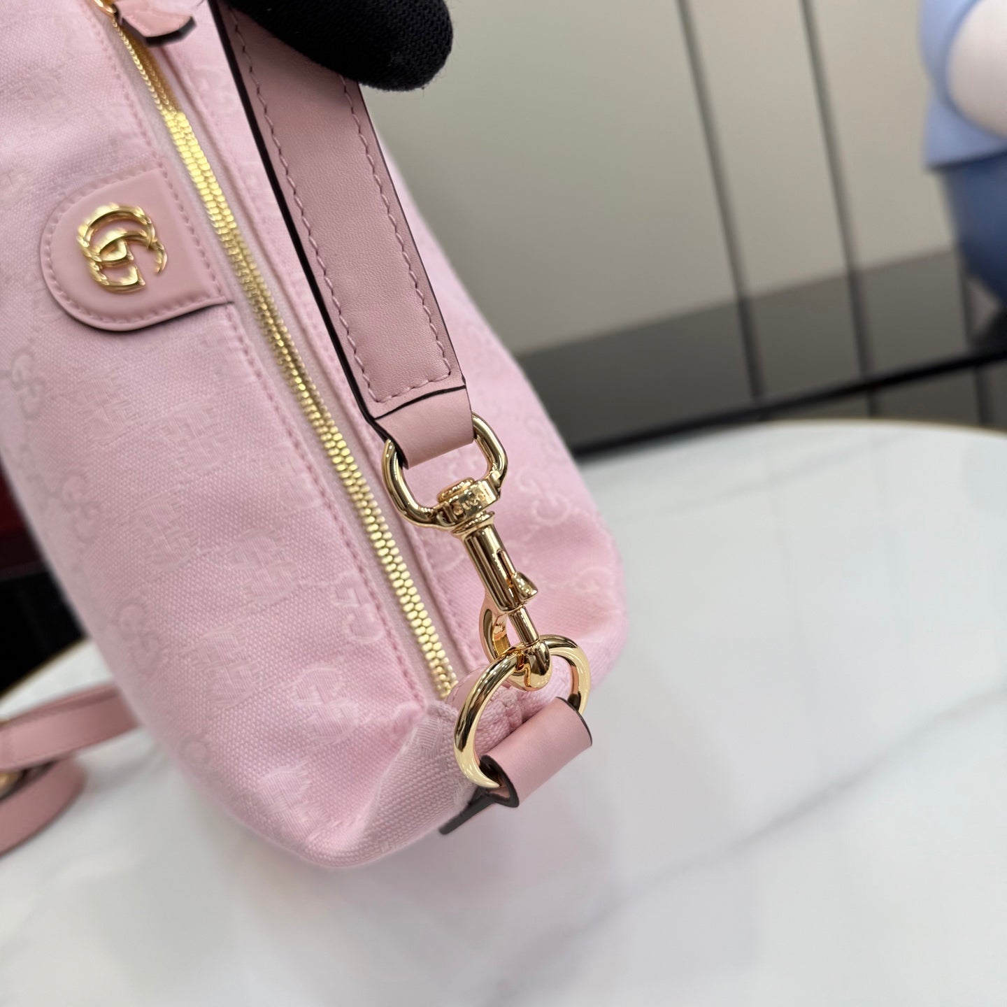 Pink strap detail with gold lobster clasp and ring hardware on zip-top bag.