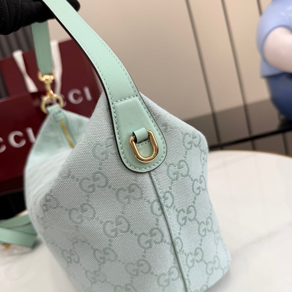 Gucci hobo bag side detail: gold D-ring, light blue strap, and GG monogram canvas