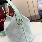Gucci hobo bag side detail: gold D-ring, light blue strap, and GG monogram canvas