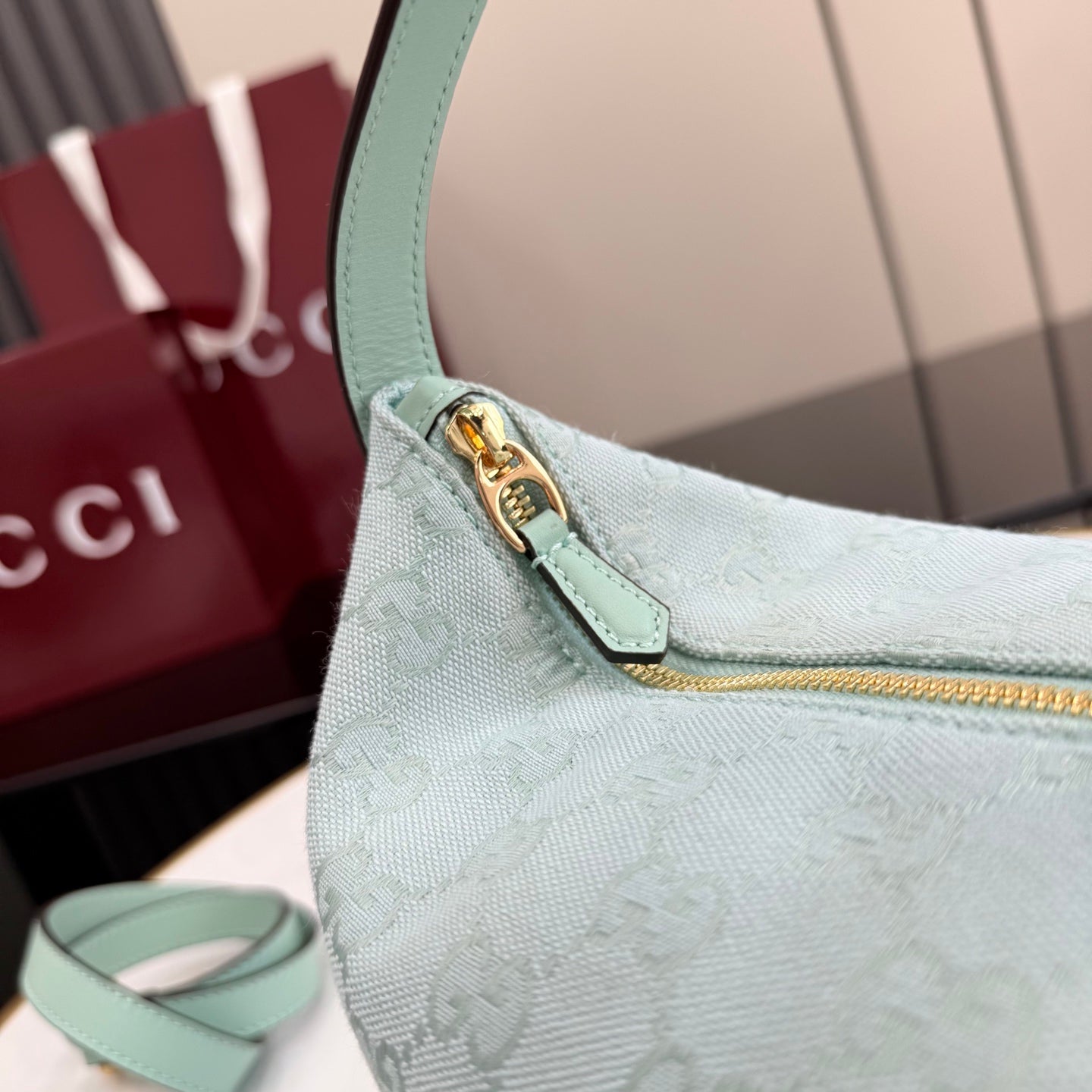 Gucci hobo bag close-up: light blue strap with gold clasp and GG monogram texture