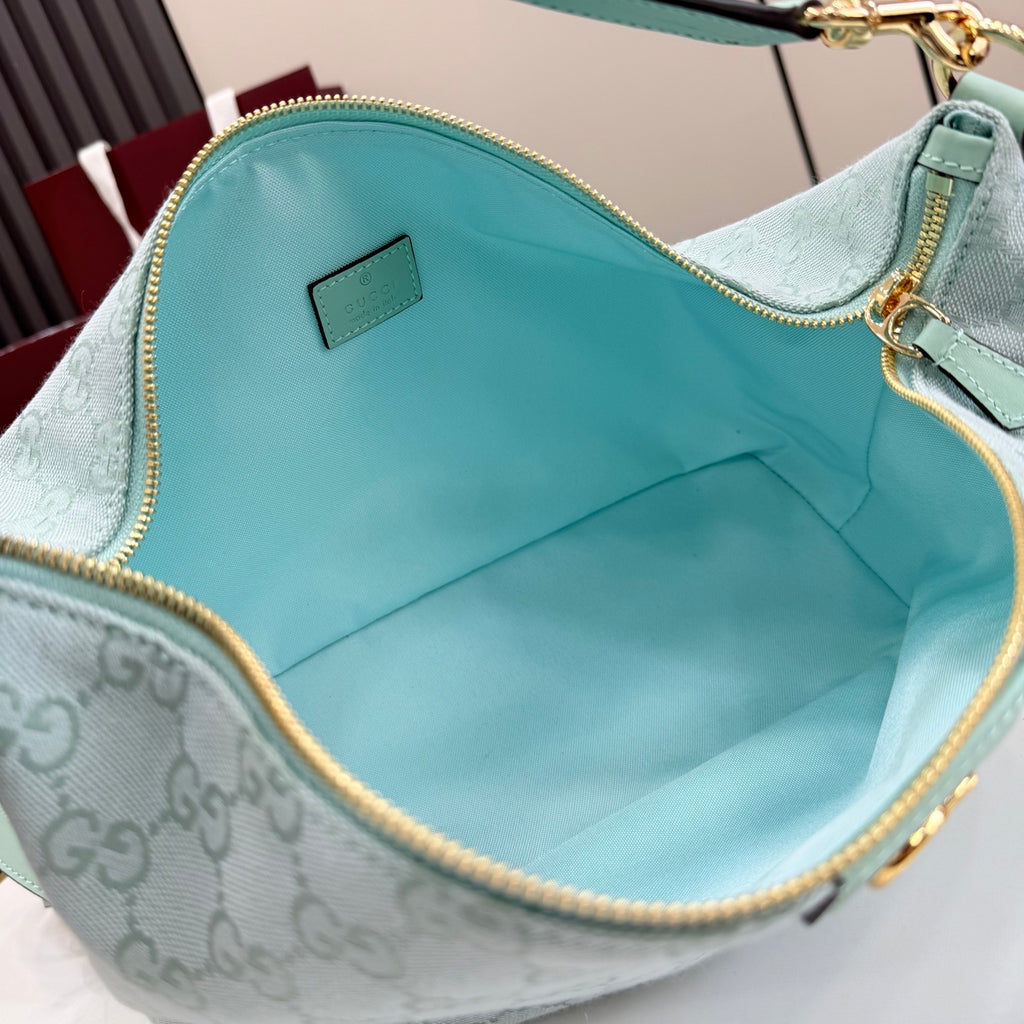 Gucci hobo bag interior with teal fabric lining and gold zipper trim, top opening visible