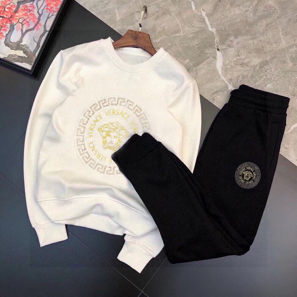 White sweatshirt and black jogger set with gold Medusa emblem and small round logo patch